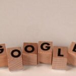 Wooden alphabet blocks forming the word 'Google' on a plain background, arranged playfully.